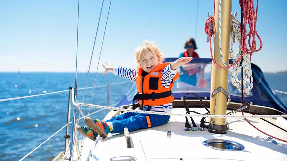 Happy child with life jacket on sailboat